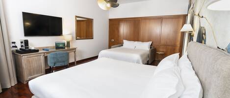 A hotel room with a large bed, a desk with a computer, a flat-screen TV, and a wooden headboard.