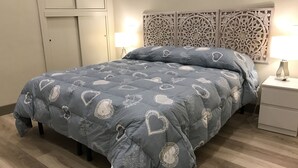 A bed with a grey quilt featuring heart patterns, a decorative headboard, and bedside lamps. - Dimora Spina (Ferrazzano)