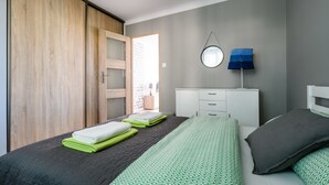 A bedroom with a bed, a wardrobe, a desk, and a lamp. - Chmielna Deluxe (Warsaw)