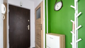A room with a wooden door, a white cabinet, and a green wall with a clock. - Chmielna Deluxe (Warsaw)