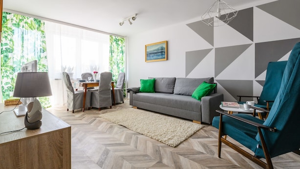 A modern living room with a sofa, a chair, a desk, and a lamp. - Chmielna Deluxe (Warsaw)