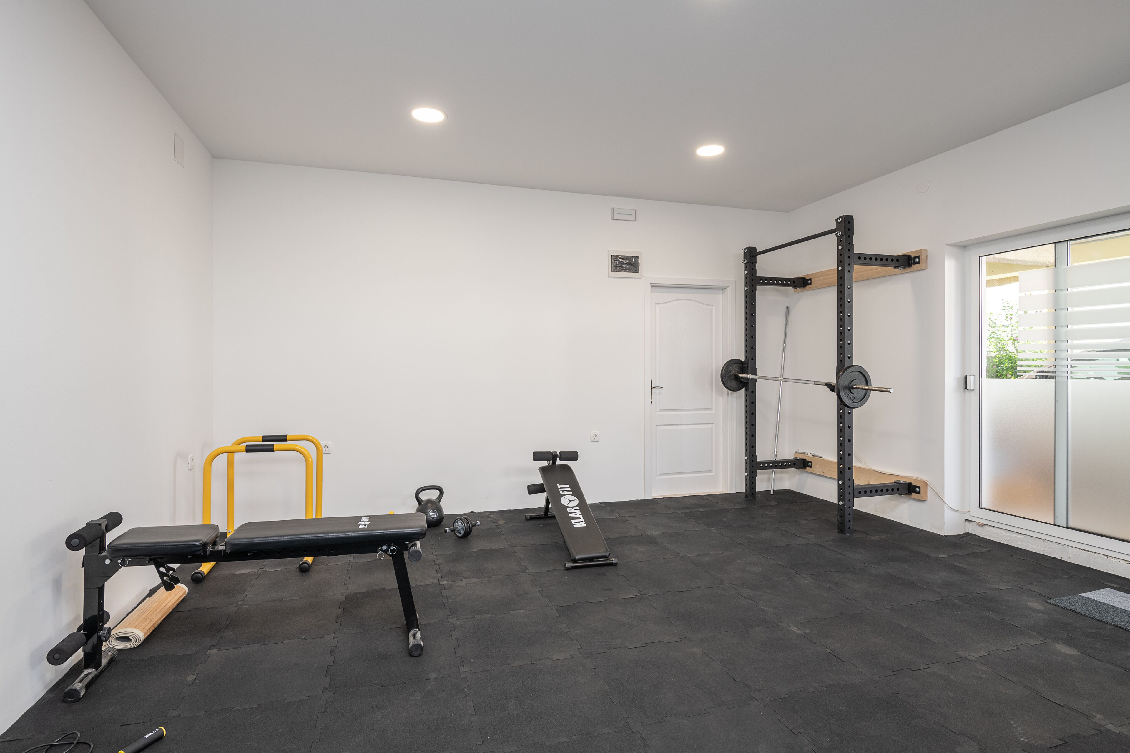 A gym with a bench press, squat rack, and various weights.
