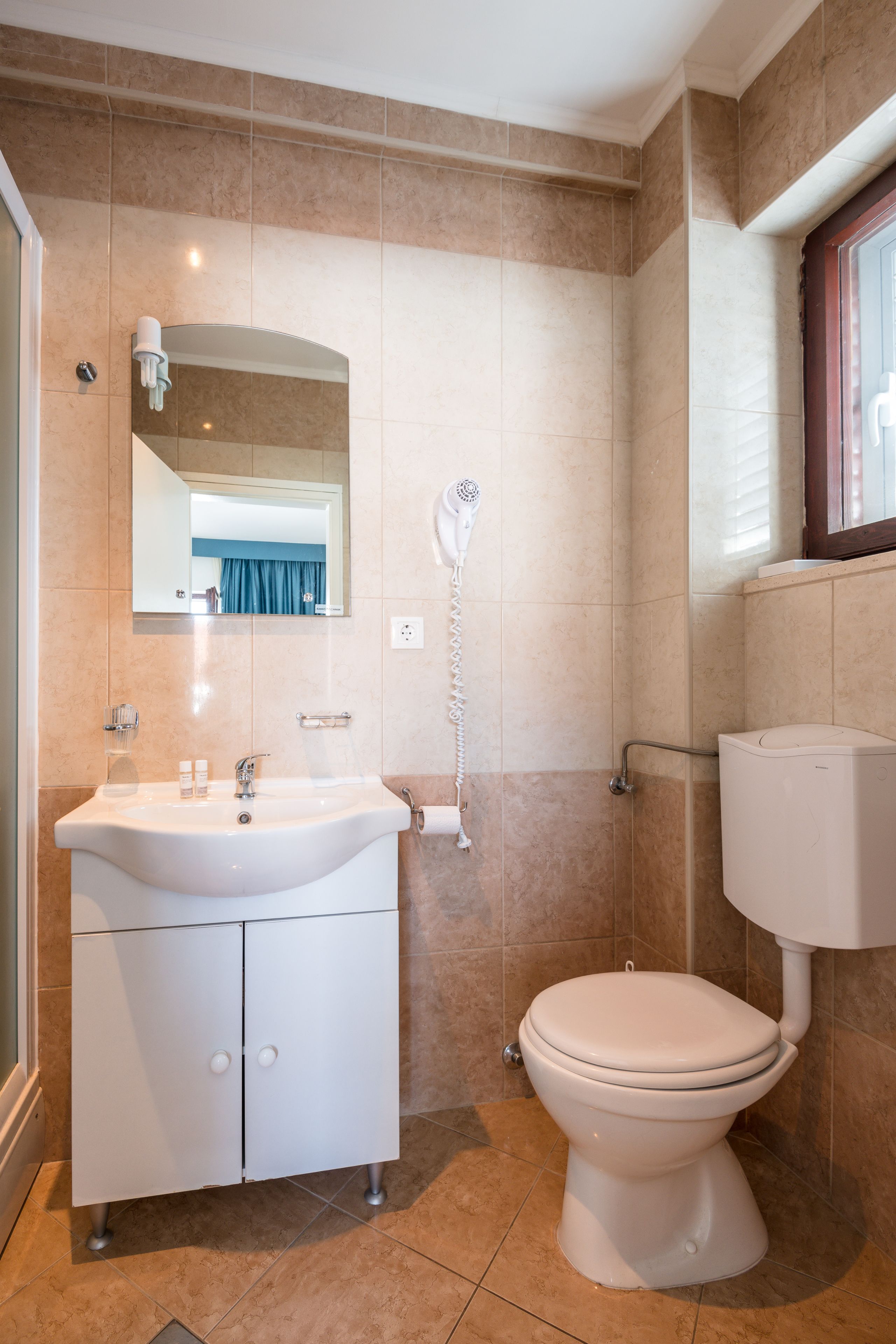 A bathroom with a white sink, mirror, and toilet.
