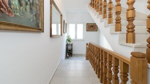 Una escalera con balaustres de madera, un cuadro en la pared y una ventana en la parte superior.