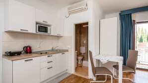 A compact kitchen with a microwave, kettle, and sink. There's a small dining area with a table and chairs. - Villa Voinic 3 (Konavle)