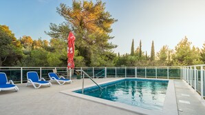 A swimming pool with blue lounge chairs and a red umbrella. - Villa Voinic 3 (Konavle)