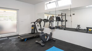A gym with treadmills, an elliptical, and a punching bag. - Villa Voinic 3 (Konavle)