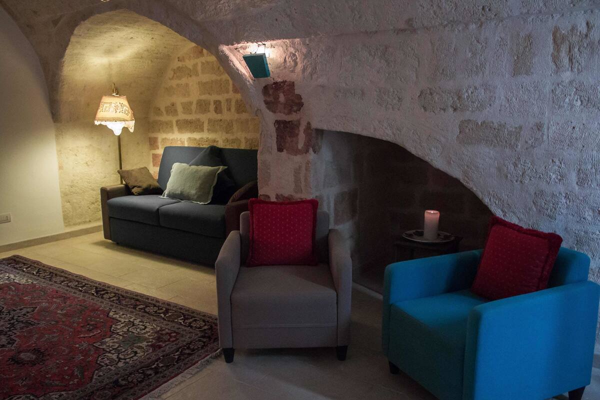 Una sala de estar acogedora con una pared de piedra, una chimenea, un sofá, una silla y un sillón azul.