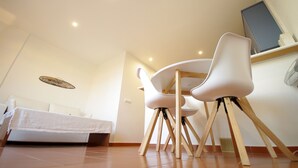 A modern dining area with a white table and chairs, a ceiling light, and a wall-mounted TV.