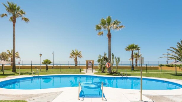 A swimming pool with a clear view of the beach in the background.