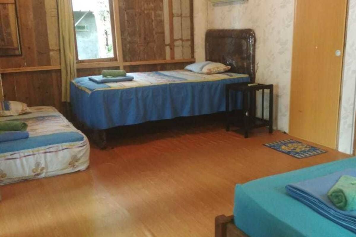 A room with two beds, a wooden floor, a window, and a door.