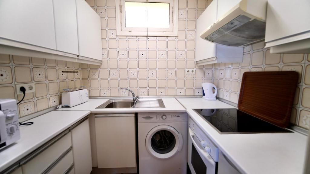 Une cuisine de taille réduite équipée d’un lave-linge, d’un évier et d’un grille-pain.