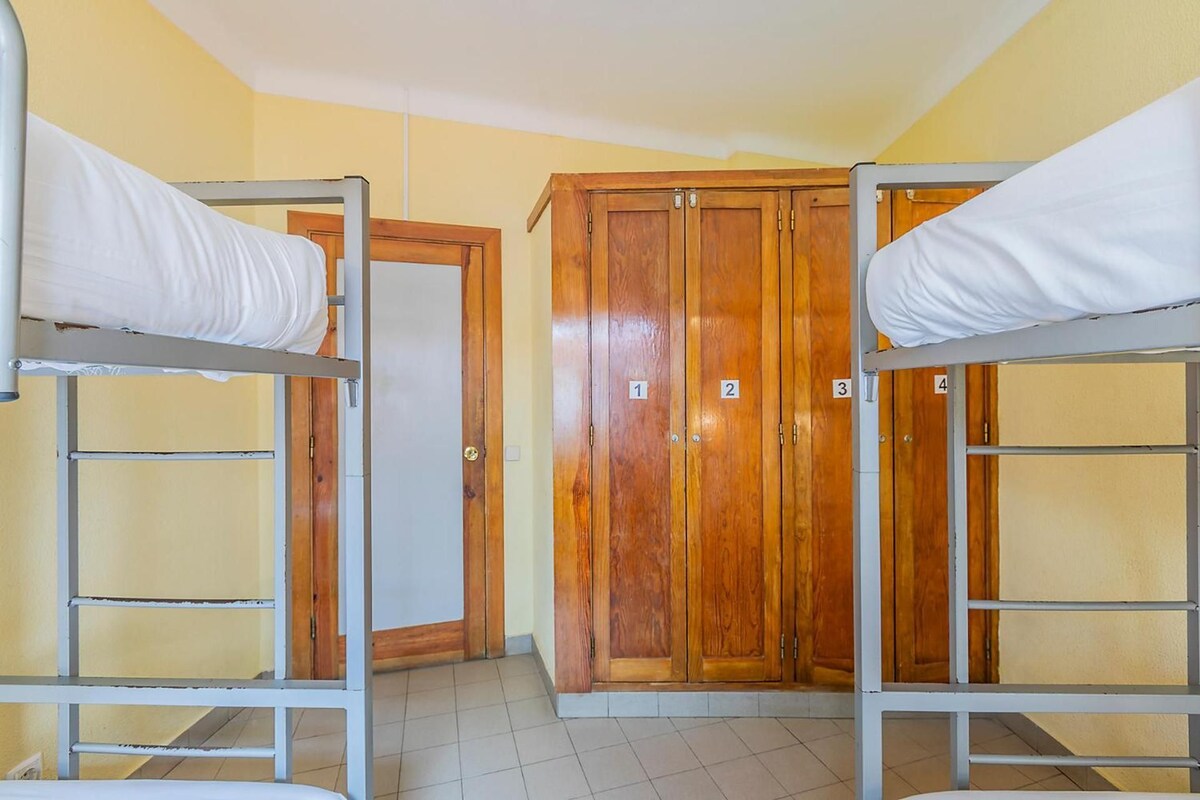Una habitación con literas y un armario de madera con puertas numeradas.