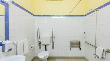 A bathroom with a toilet, hand dryer, and a shower.