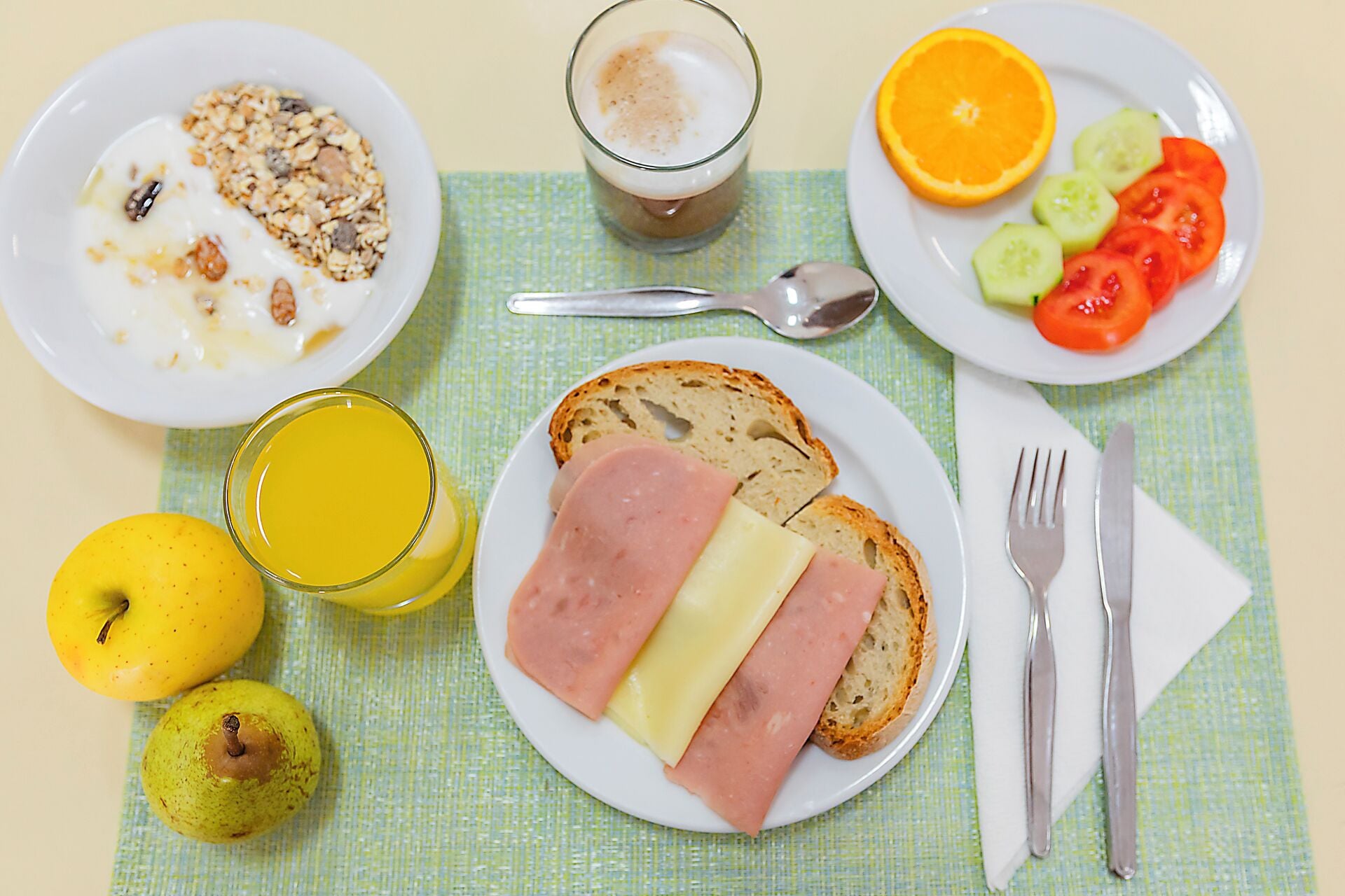 Disposição para o café da manhã com pratos de comida, um copo de suco e uma cesta de frutas.