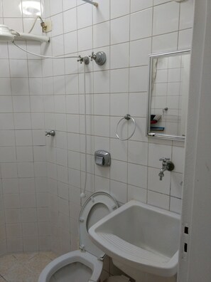A bathroom with a toilet, sink, and shower. - Kitnet em São Vicente (Sao Vicente)