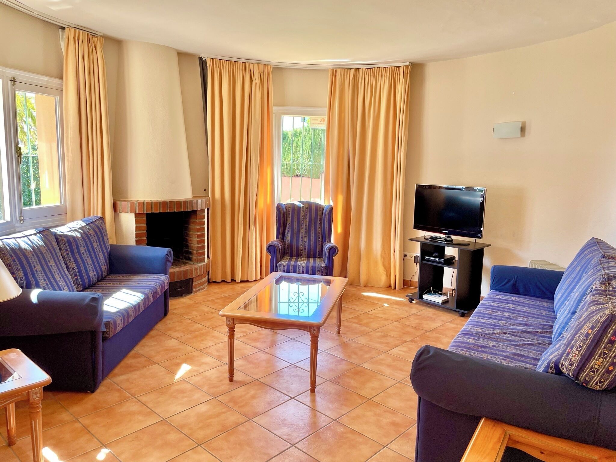Una sala de estar con chimenea, dos sofás, una mesa de centro y un televisor.