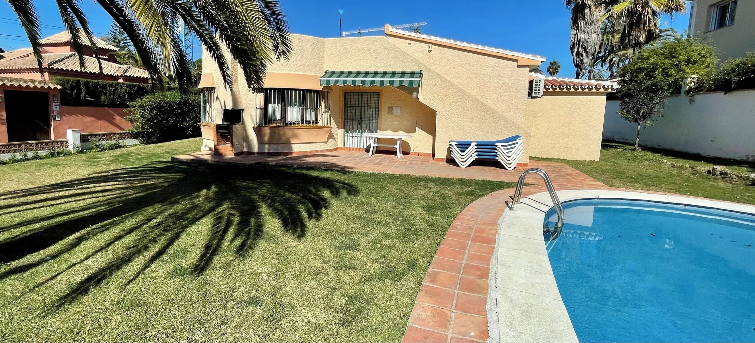 Ein Wohnhaus mit Swimmingpool, überdachter Terrasse und gepflegtem Rasen.