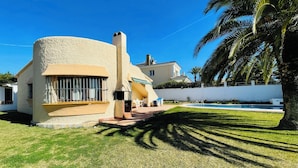 Ein modernes Haus mit einer geschwungenen Fassade, einem Pool und einem gepflegten Rasen.