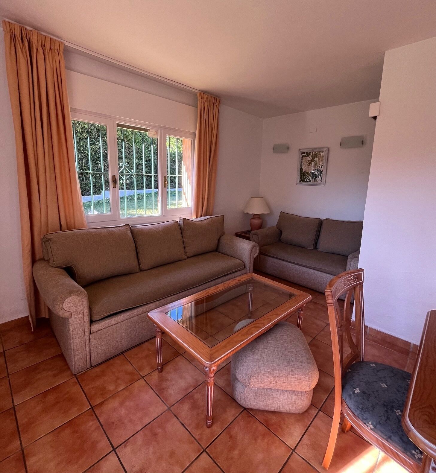 Ein Wohnzimmer mit zwei Sofas, einem Glastisch und einem Holzstuhl.