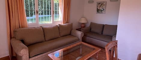Ein Wohnzimmer mit zwei Sofas, einem Glastisch und einem Holzstuhl.