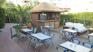 Eine Außenpatio-Terrasse mit einer Bar und Sitzgelegenheiten unter einem Reetdach.