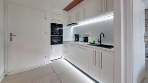 A modern kitchen with white cabinets, a built-in oven, and a coffee maker.