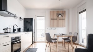 A modern kitchen with a built-in oven, a dining area with a table and chairs, and a large window providing natural light.