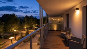 A balcony with wooden flooring, outdoor furniture, and string lights.
