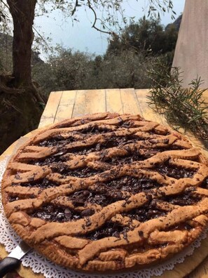 A round pie with a lattice crust on a wooden table outdoors. - Agririfugio Molini (Camogli)