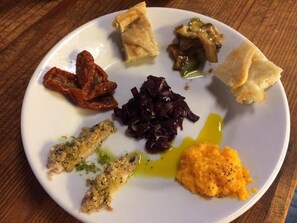 A white plate with various food items including a piece of pie, a serving of red cabbage, a portion of mashed potatoes, and a small piece of bread. - Agririfugio Molini (Camogli)