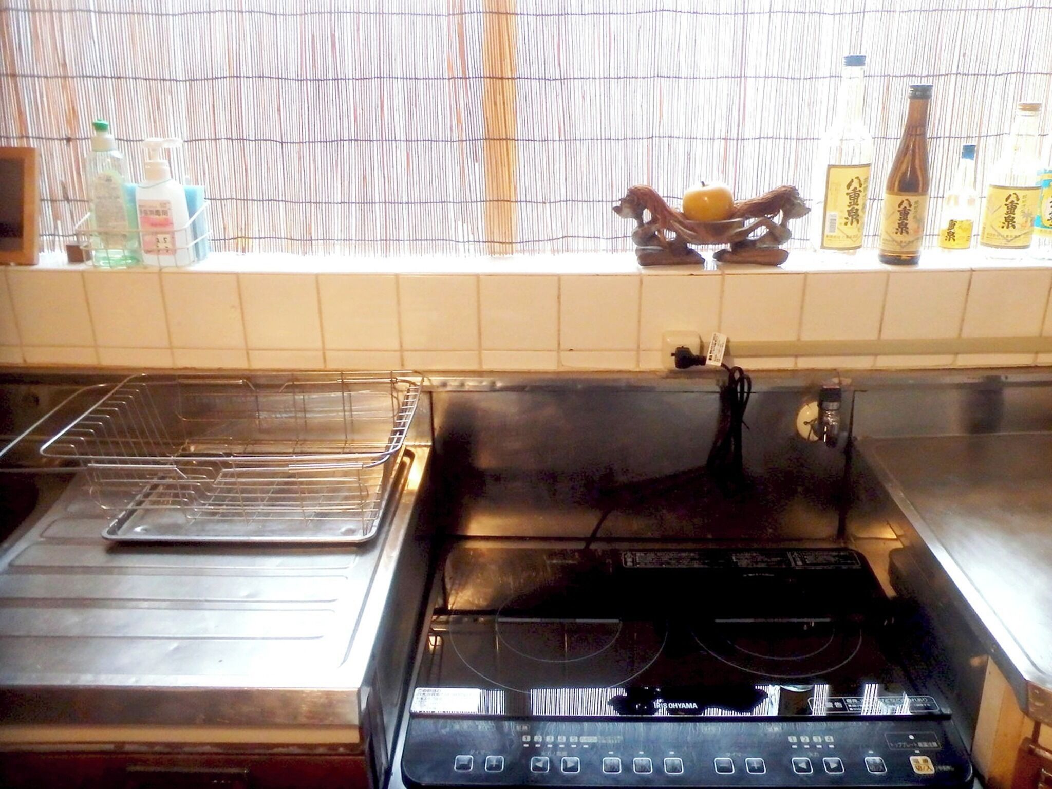 A kitchen with a stove, a sink, and a window with bottles on the sill.
