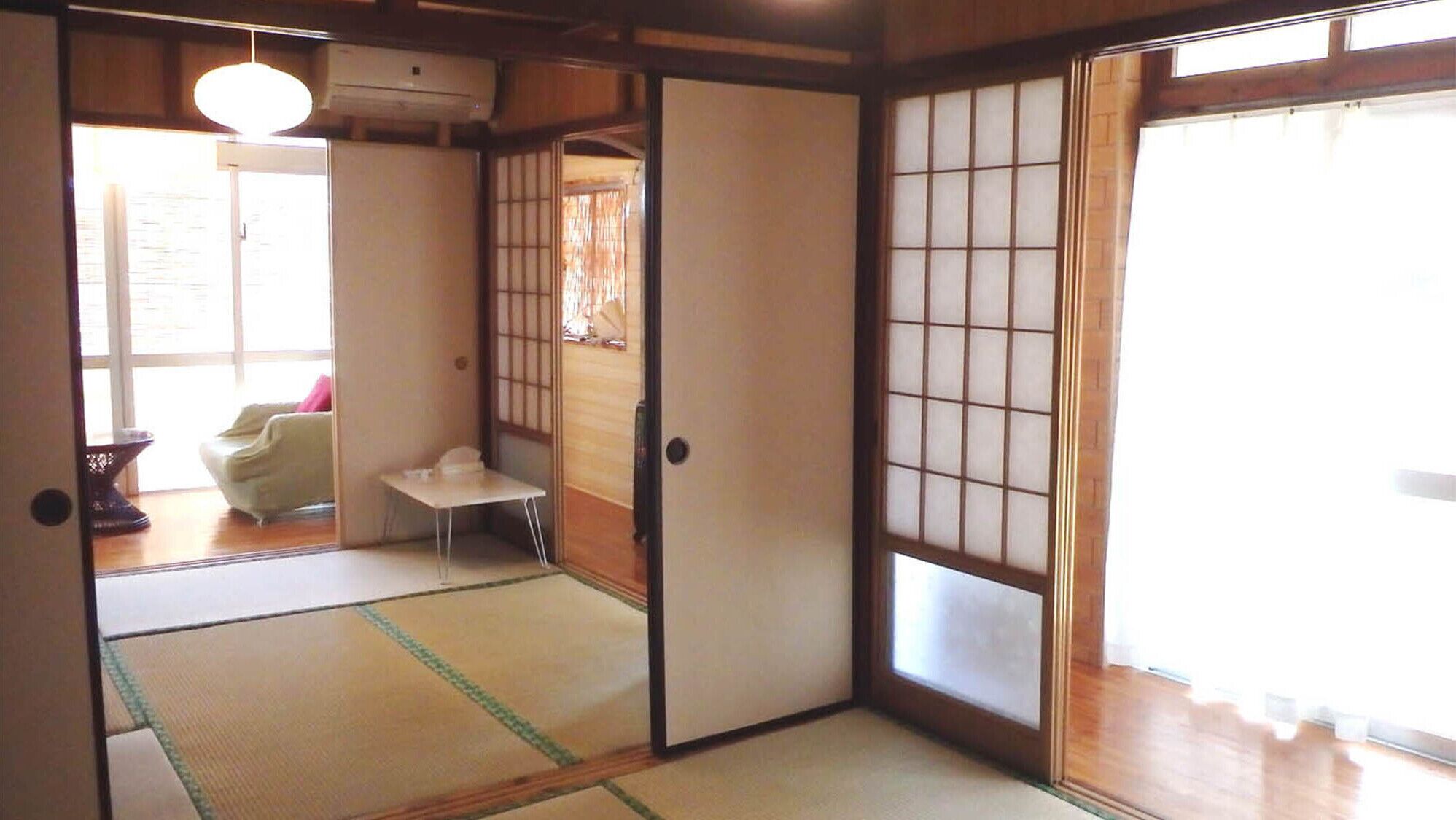 A traditional Japanese room with tatami flooring, sliding doors, and a small table.