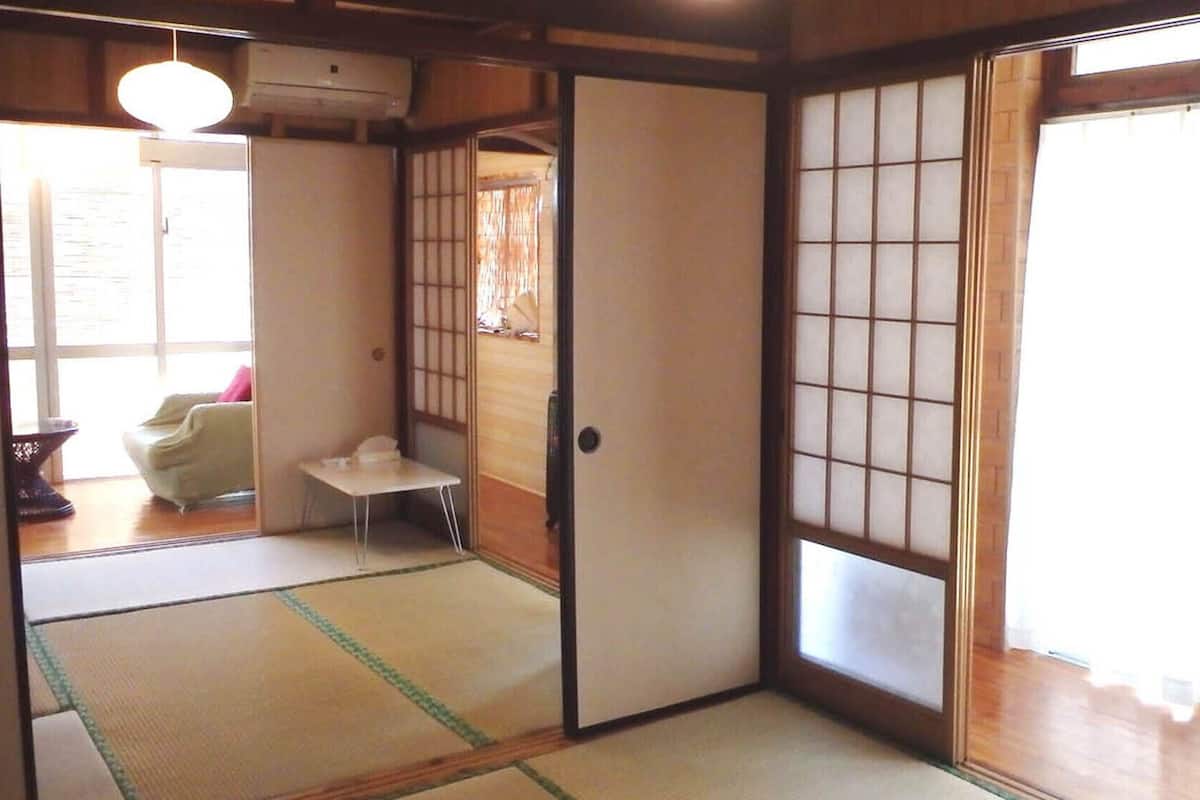 A traditional Japanese room with tatami flooring, sliding doors, and a small table.
