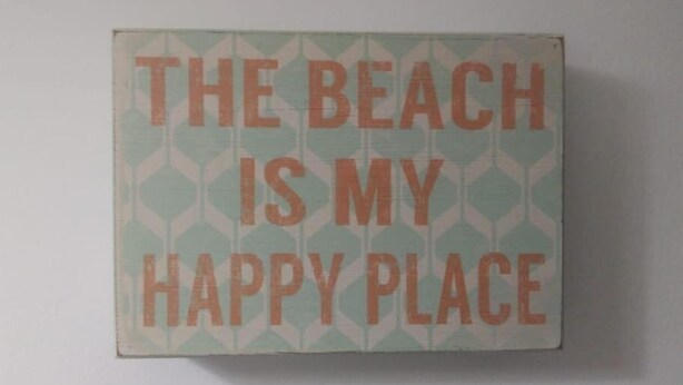 A square sign with the text "THE BEACH IS MY HAPPY PLACE" in bold letters. - Apartamento Caraguatatuba Prainha (Caraguatatuba)