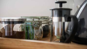 Een keukenkastje met glazen potten, een koffiepot en een waterkoker.
