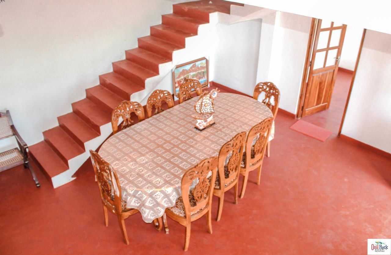 Un comedor con una mesa redonda, seis sillas y una escalera con escalones rojos.