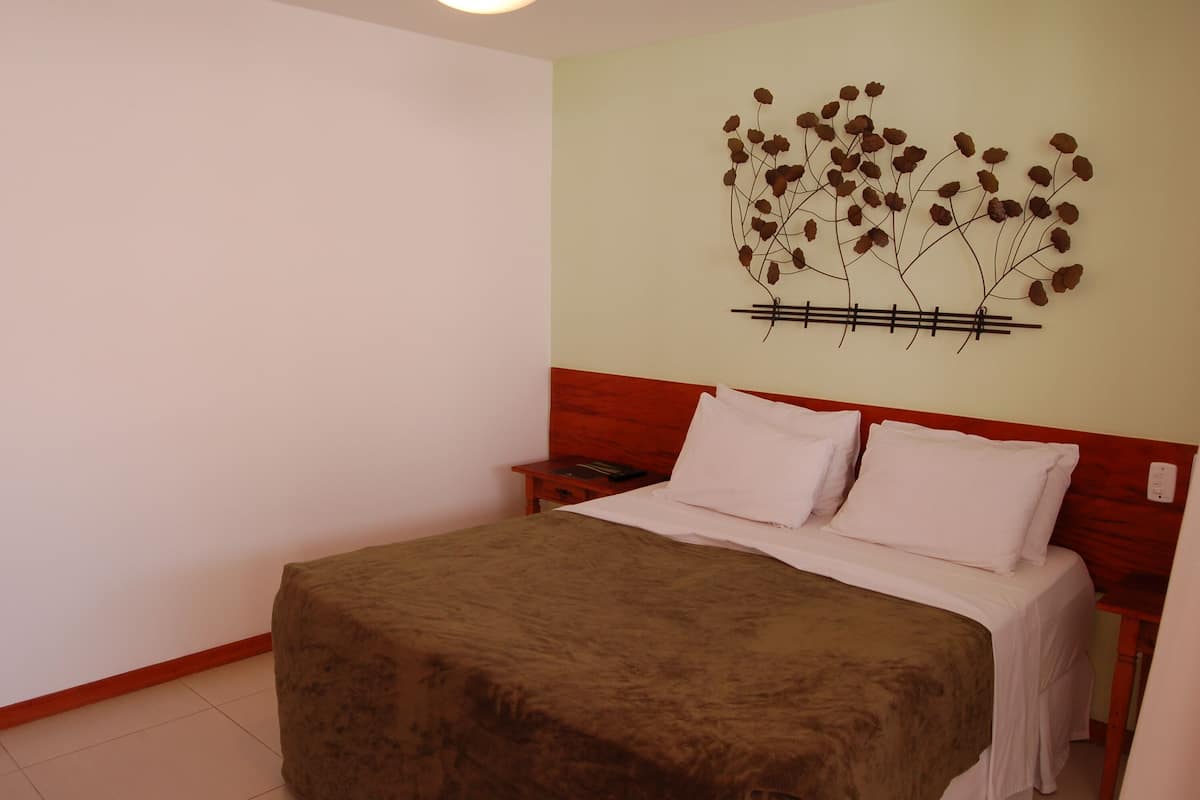 Un lit bien fait, avec une couverture marron, une tête de lit en bois et un élément décoratif fixé au mur.