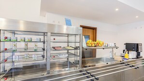Una cocina comercial con electrodomésticos de acero inoxidable, incluyendo un refrigerador lleno de bebidas y un mostrador con alimentos.