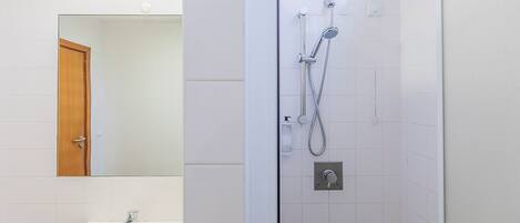 A bathroom with a white sink, a mirror, and a shower with a handheld showerhead.