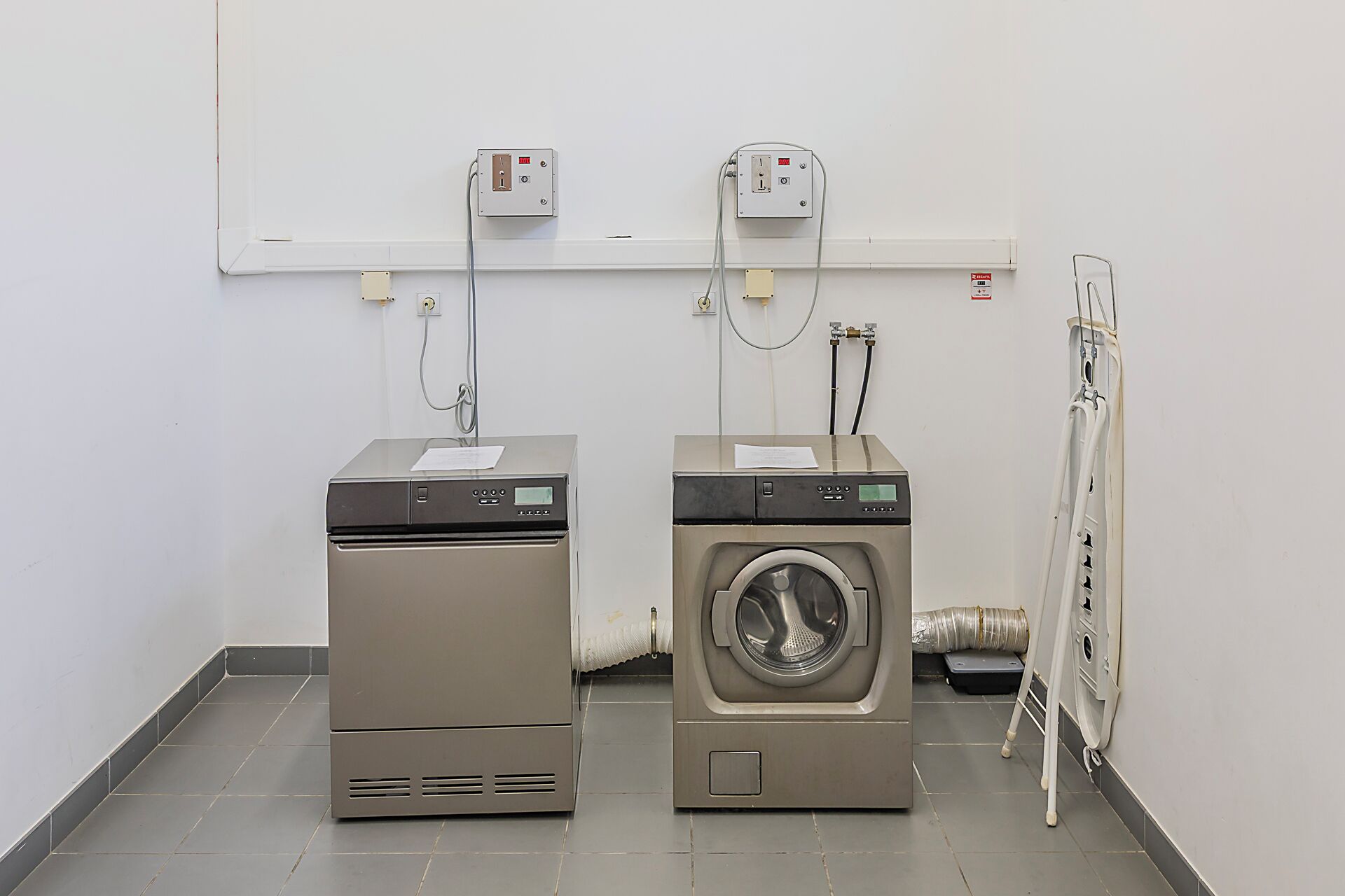 Two stacked laundry machines in a room with a tiled floor and a white wall.