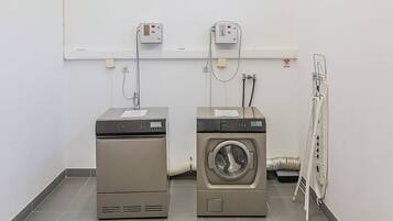Two stacked laundry machines in a room with a tiled floor and a white wall.