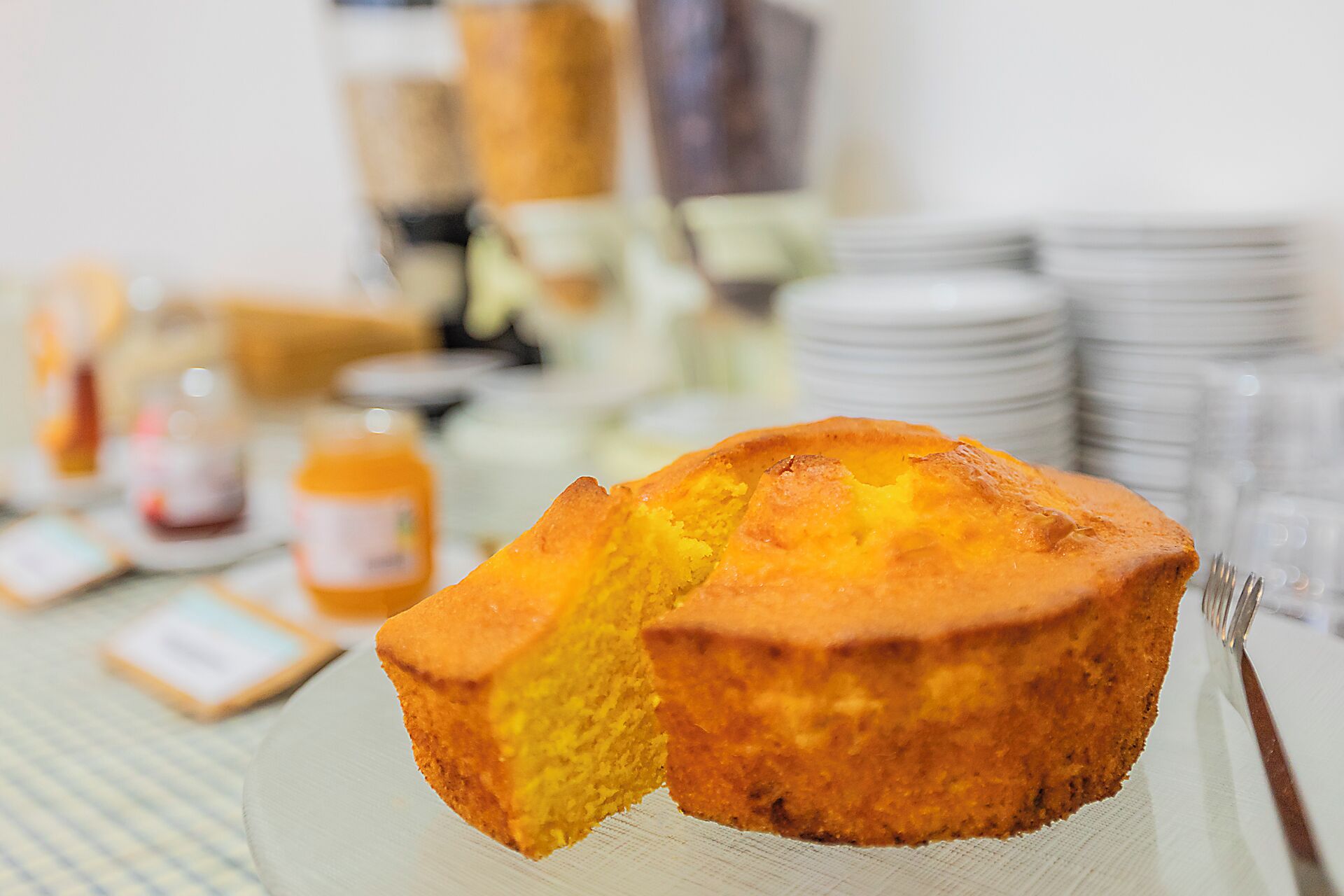 A muffin on a plate with a blurred background of a dining area.
