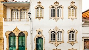 Un edificio con varias ventanas, un balcón y una puerta verde.