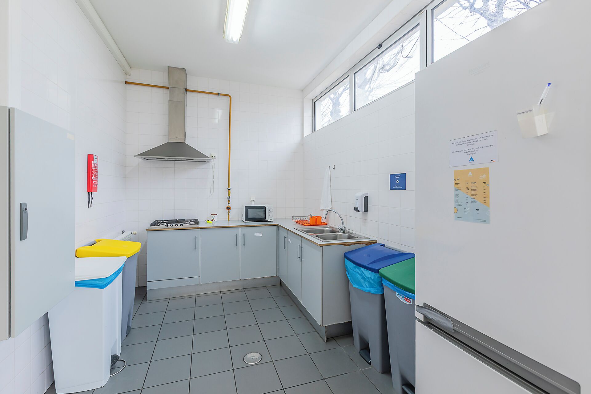 Een keuken met een gasfornuis, magnetron, spoelbak en een raam.
