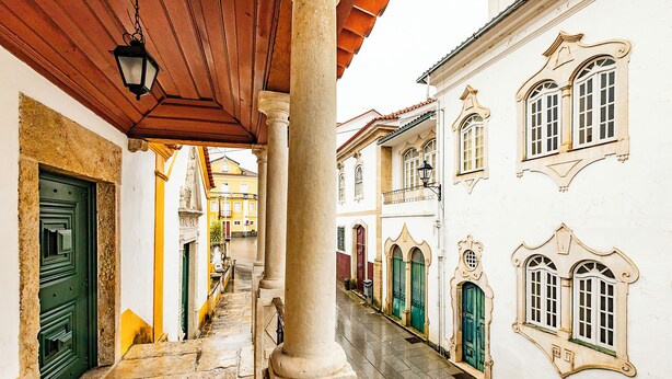 Una calle estrecha con edificios de fachadas ornamentadas y una escalera de piedra.