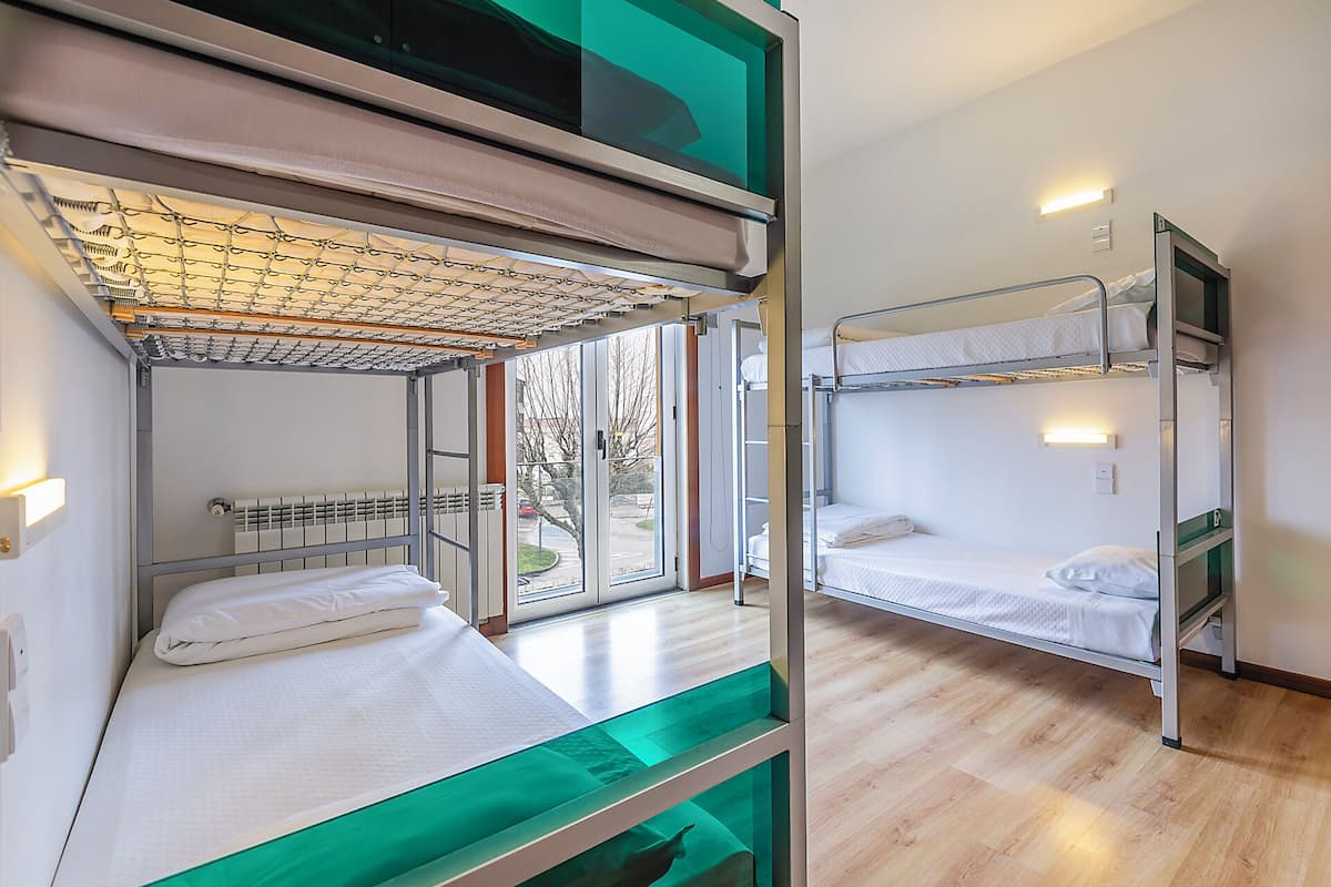 Camera con letto a castello, finestra, termosifone e mensola verde.