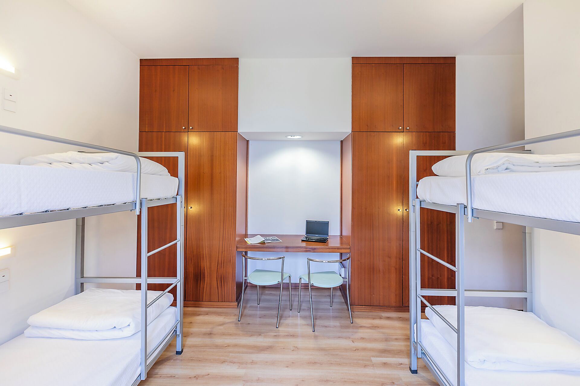 Habitación compartida con dos literas, un escritorio y dos sillas.