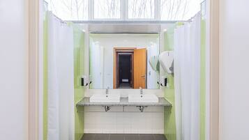 Un baño moderno con dos lavamanos, un espejo y una zona de ducha.