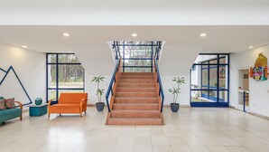 Een ruim interieur met een centrale trap, grote ramen en potplanten.
